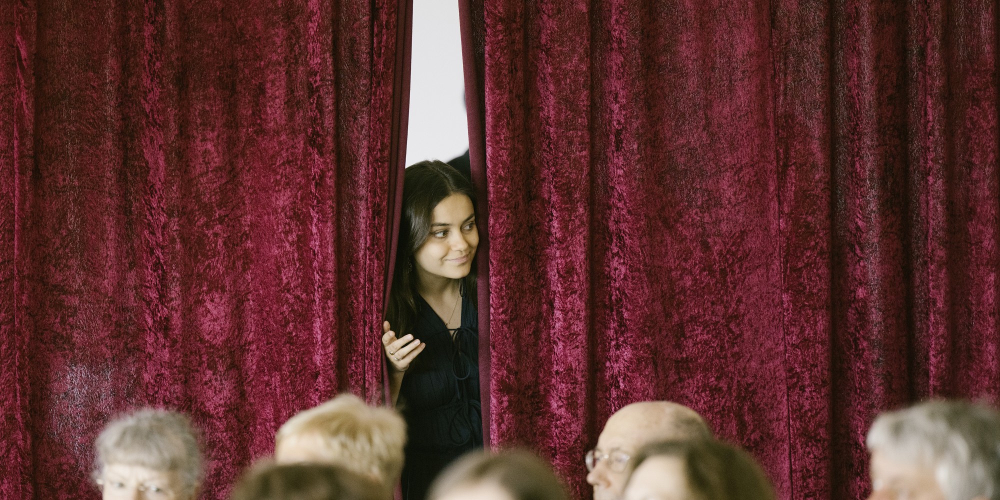 Musikerin schaut durch Bühnenvorhang